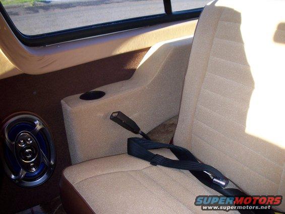 Car interior with tan seats, a speaker, and a seatbelt. A cup holder is visible