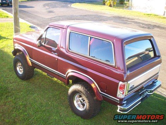 Maroon Ford Bronco parked on grass, showing its side and rear