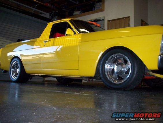 Yellow pickup truck, side view, lowered stance, custom wheels, red interior visible