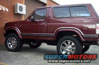 Maroon 1985 Ford Bronco with chrome wheels parked outside