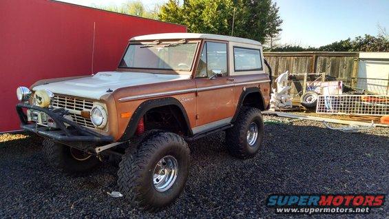 Brown and white Ford Bronco with aftermarket bumper and large tires