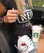 1990 Max II - A woman in a car holds a Starbucks cup while a Hello Kitty gun holster rests on her lap.