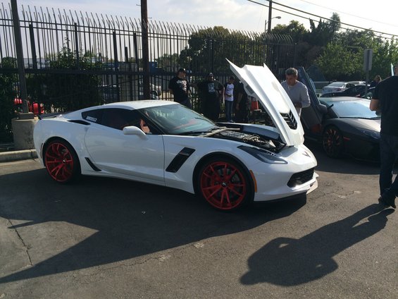 White Chevrolet Corvette Stingray with red wheels, hood open, parked outdoors