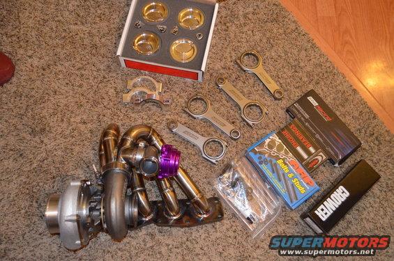 Turbocharger, connecting rods, and engine build kit laid out on carpet