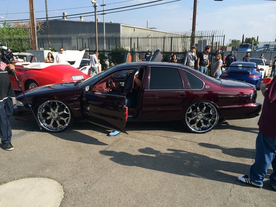 Maroon 1996 Chevrolet Impala with custom rims and doors open. Other cars visible in background