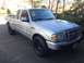 2010 Ford Ranger - This silver Ford Ranger pickup truck is shown from a 3/4 front angle, parked on a driveway with trees and a wooden fence in the background.