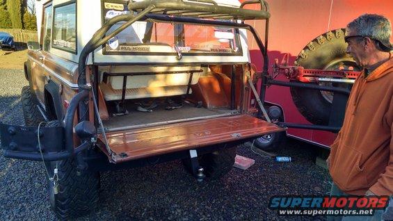 Rear view of brown off-road SUV with tailgate open and roll cage