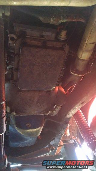 Undercarriage of a vehicle showing transmission pan, exhaust pipe, and suspension components