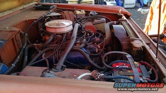 Engine bay with V8 engine, air filter, radiator, and battery visible