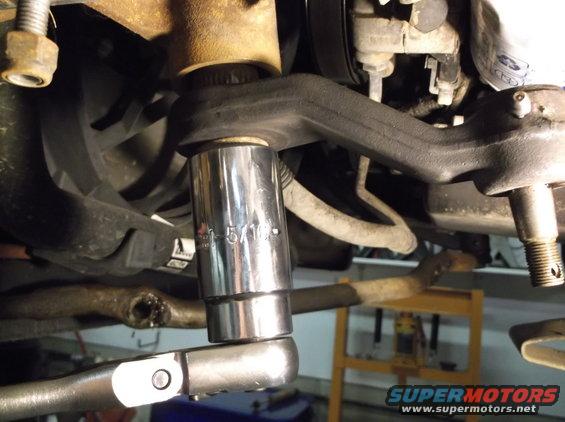 Close-up of a suspension component with a 5/16 socket wrench attached