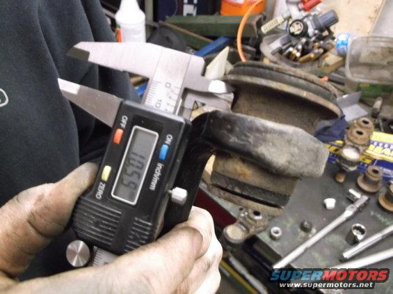 Digital caliper measuring suspension part at 10.59 inches
