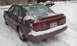 1996 Subaru Legacy - A 1996 Subaru Legacy sedan is partially covered in snow on a winter day.