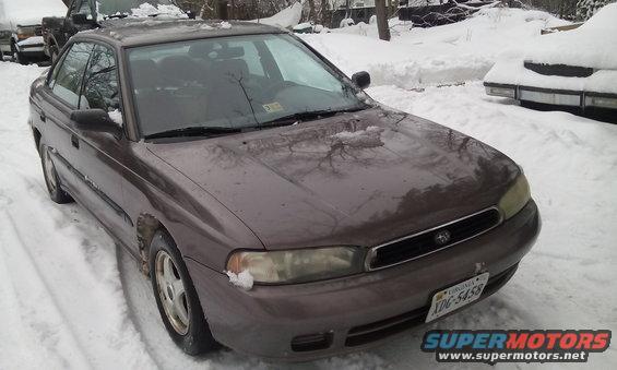 1996 Subaru Legacy sedan parked in snow, front passenger side view. Another vehicle is partially visible in the background