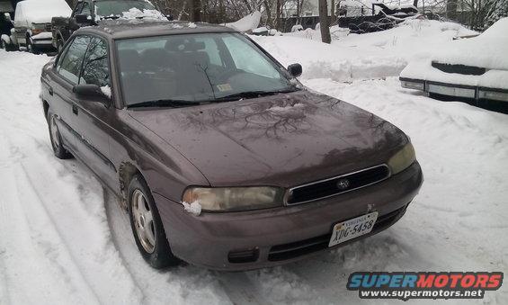 Front 3/4 view of a brown 1996 Subaru Legacy sedan parked in the snow. Another vehicle is visible behind it