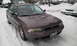 1996 Subaru Legacy - A 1996 Subaru Legacy sedan sits covered in snow, with other vehicles partially visible in the background.