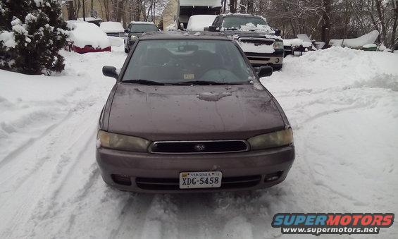 Brown sedan with snow on hood, front view, parked in a snowy driveway