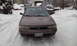 1996 Subaru Legacy - A brown sedan sits in a snow-covered driveway, with other vehicles visible in the background.
