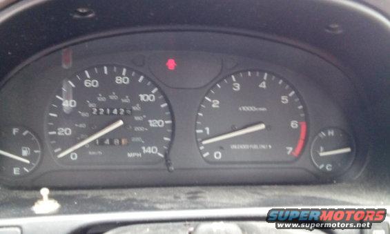 Car dashboard with speedometer, tachometer, fuel gauge, and warning lights. Odometer reads 221423