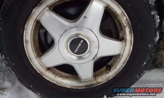 Close-up of a Subaru wheel with a black center cap that says SUBARU. Tire is black