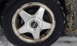 1996 Subaru Legacy - A Subaru wheel and tire are shown in a snowy environment. The wheel features a five-spoke design and a central Subaru logo.