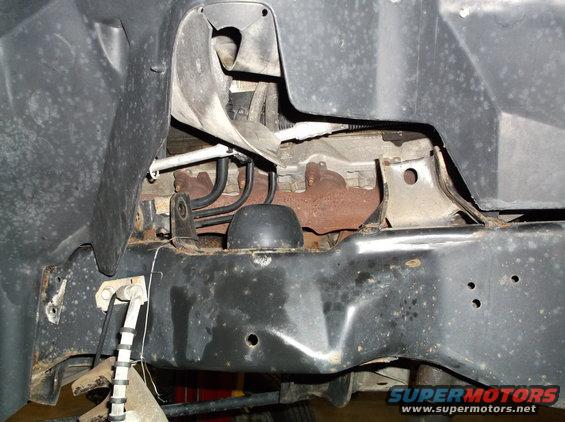 Underside view of vehicle frame with exhaust manifold and suspension components visible