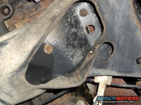 close-up of rusty metal bracket and bolts on a vehicle frame