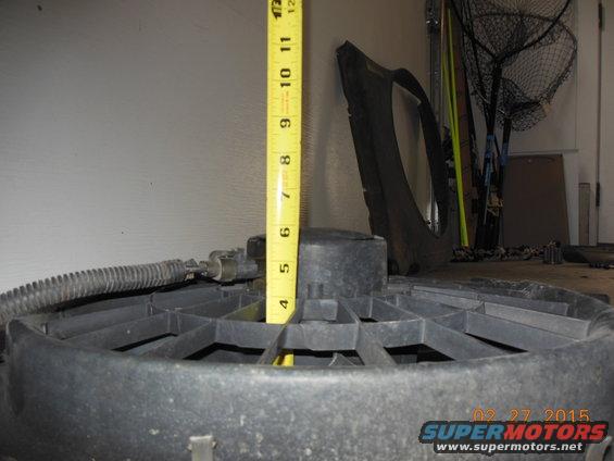 Black plastic radiator fan with a yellow measuring tape showing approximately 6 inches