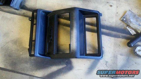 Black plastic dashboard trim piece with openings for gauges and radio