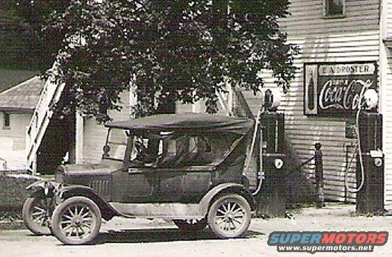 Side view of a 1925 sedan at a gas station with Coca-Cola sign
