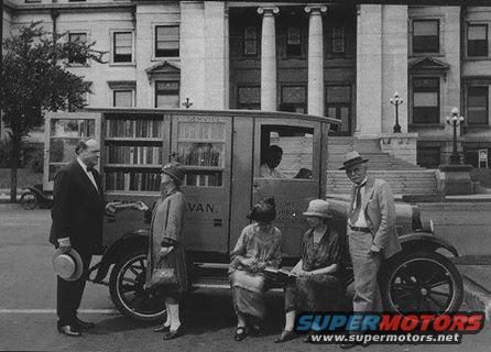 1915 mobile library van with people standing and sitting outside a building