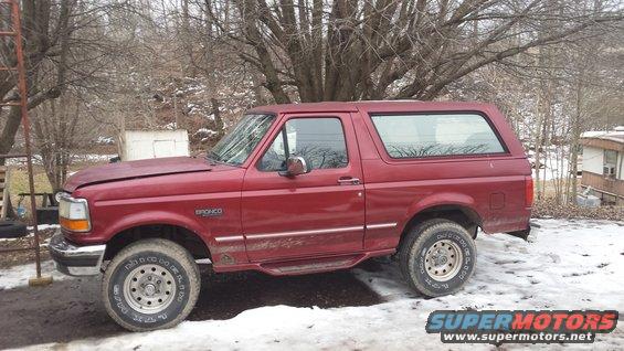 Red Ford Bronco with a dented hood and dirty side trim