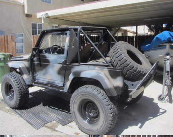 Camouflaged Suzuki Samurai with roll cage and spare tire mounted on rear bumper