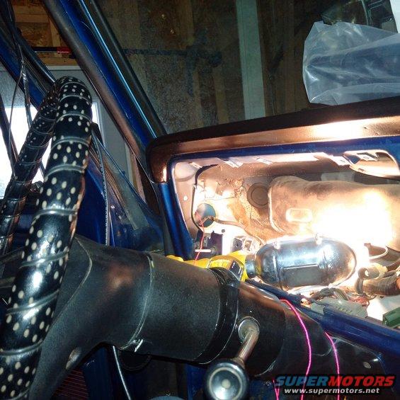 Blue car interior with black steering wheel, exposed dashboard components, and wiring