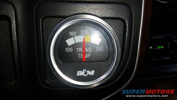 Close-up of a B&M transmission temperature gauge in a vehicle's dashboard