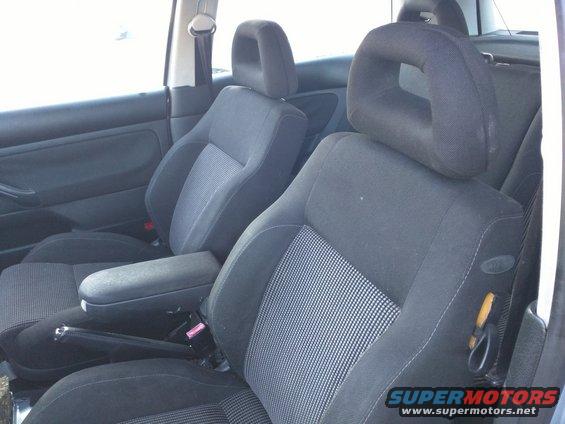 Dark fabric car interior with front seats, armrest, and seatbelts visible