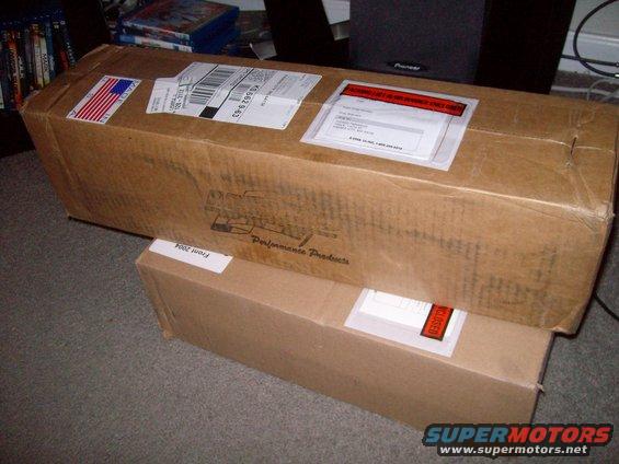 Two cardboard boxes, one labeled 'Front 2004' and 'Performance Products', stacked on a carpeted floor