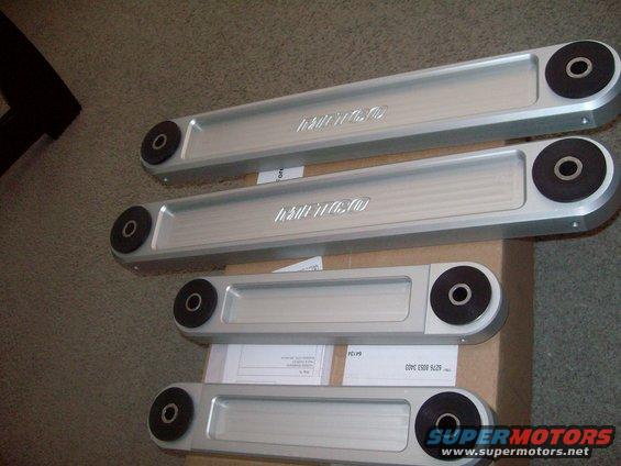 Four silver control arms with black bushings, two with embossed text
