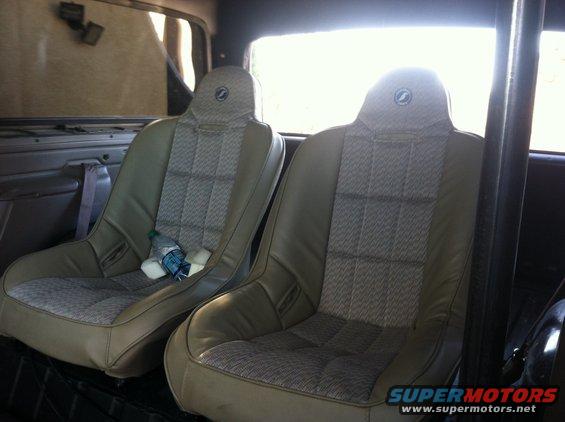 Two bucket seats inside a vehicle, with a water bottle on the left seat