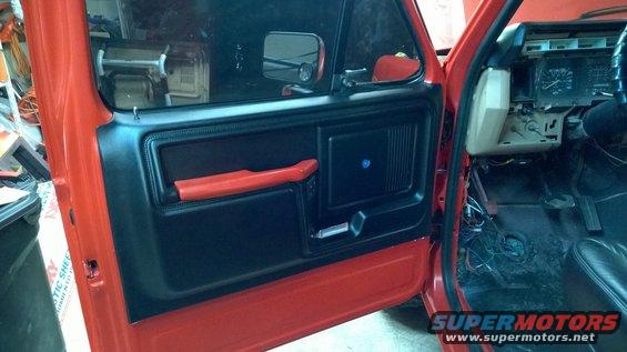 Door panel and dashboard of a red truck, showing exposed wiring under the dash