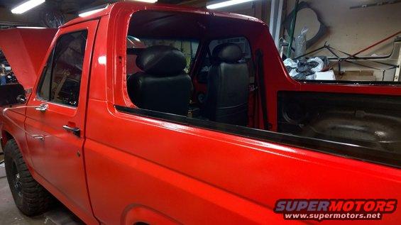 Red Ford Bronco with black interior, hood open, side view
