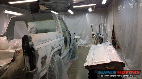 1983 Ford Bronco body covered in primer, prepped for paint in a booth