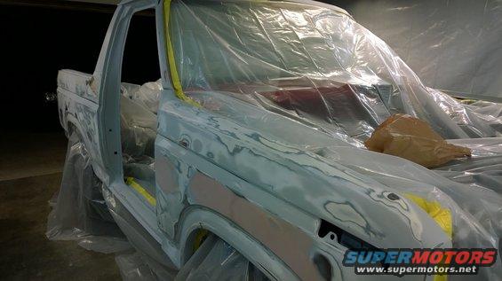 Ford pickup truck body covered in plastic sheeting, undergoing bodywork
