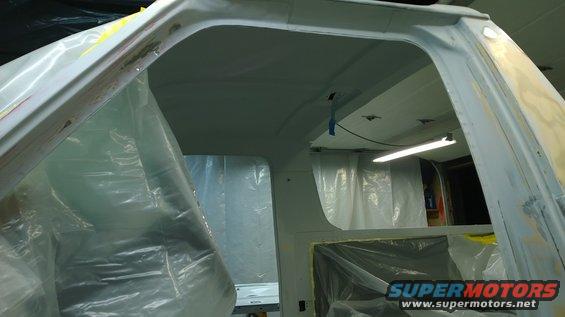 White vehicle interior with plastic sheeting, primer, and a fluorescent light