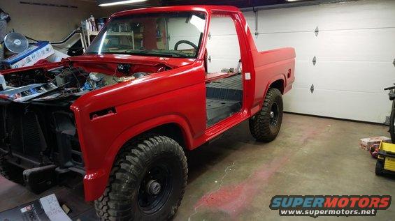 Red Ford Bronco with doors removed, engine bay open, in a garage