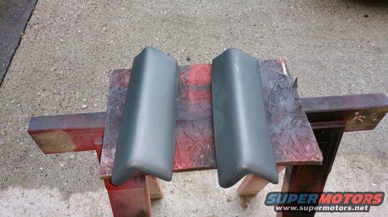 two dark gray bumper guards sitting on a red and brown wooden stand