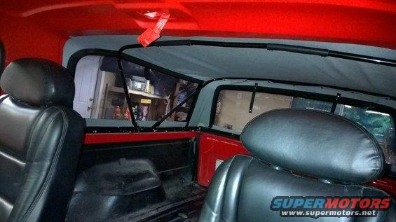 Interior of a red SUV with black leather seats and a soft top frame
