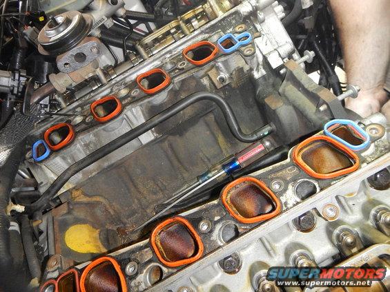 engine block with intake manifold gaskets removed, screwdriver on top