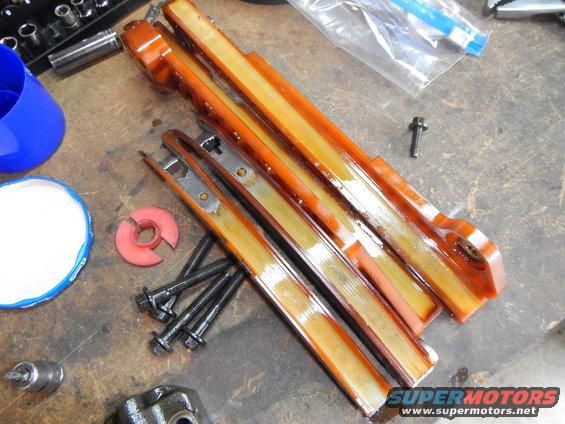 Timing chain guides and bolts laid out on a workbench