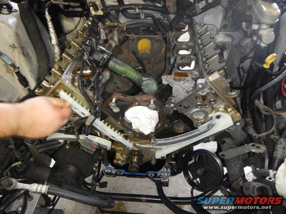 engine with timing chains exposed, hand working on it