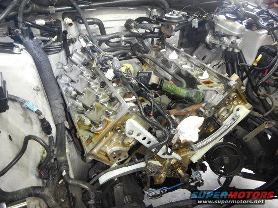 Engine bay with valve covers removed, showing internal engine components and wiring
